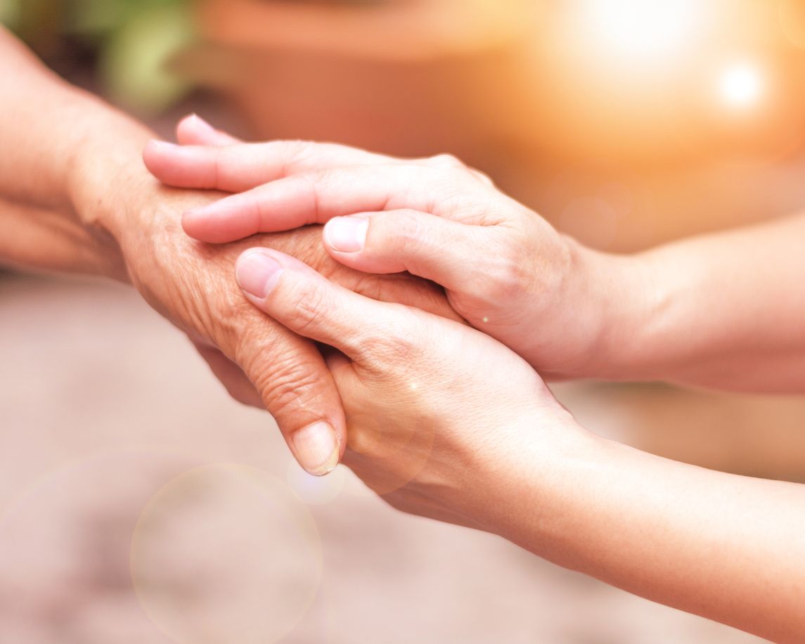 Younger hands holding an elder hand with care.