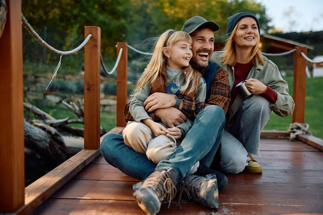 A family in wilderness outfits sitting on a bridge